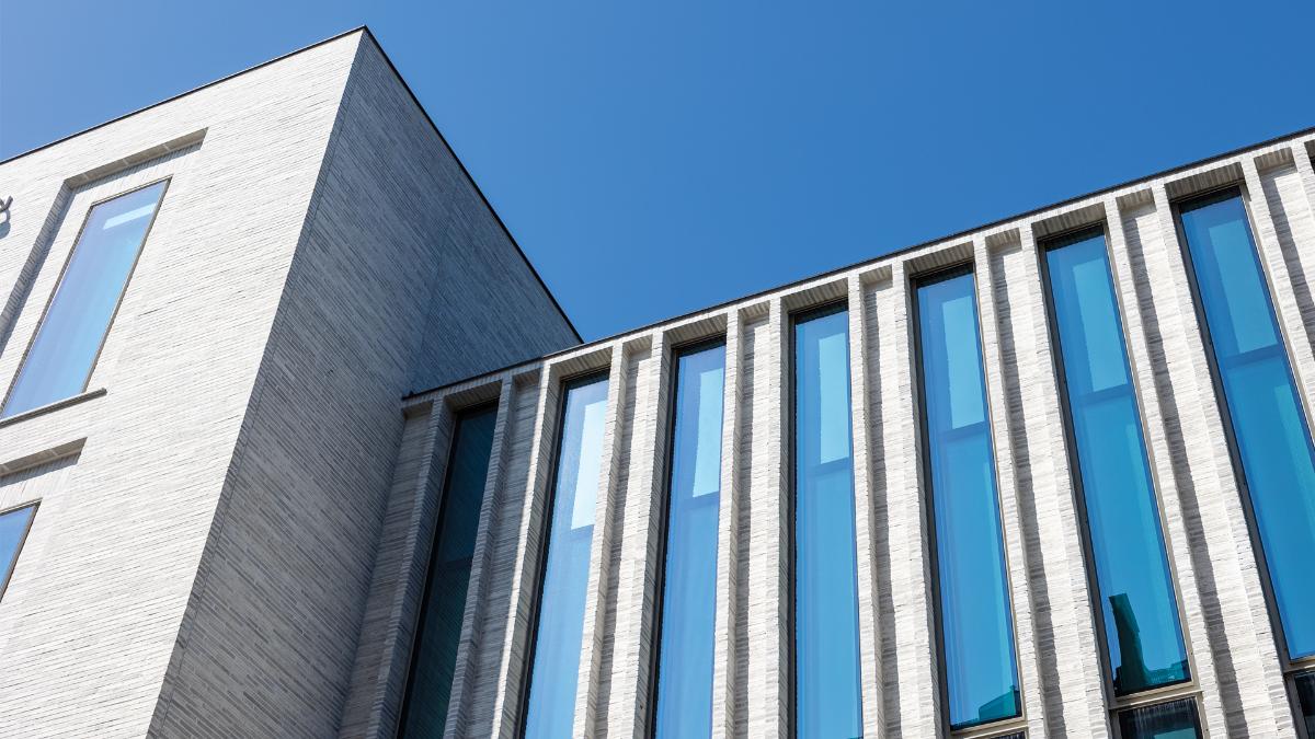 Lähikuva rakennuksesta, vaaleaa tiiltä ja lasipintoja.