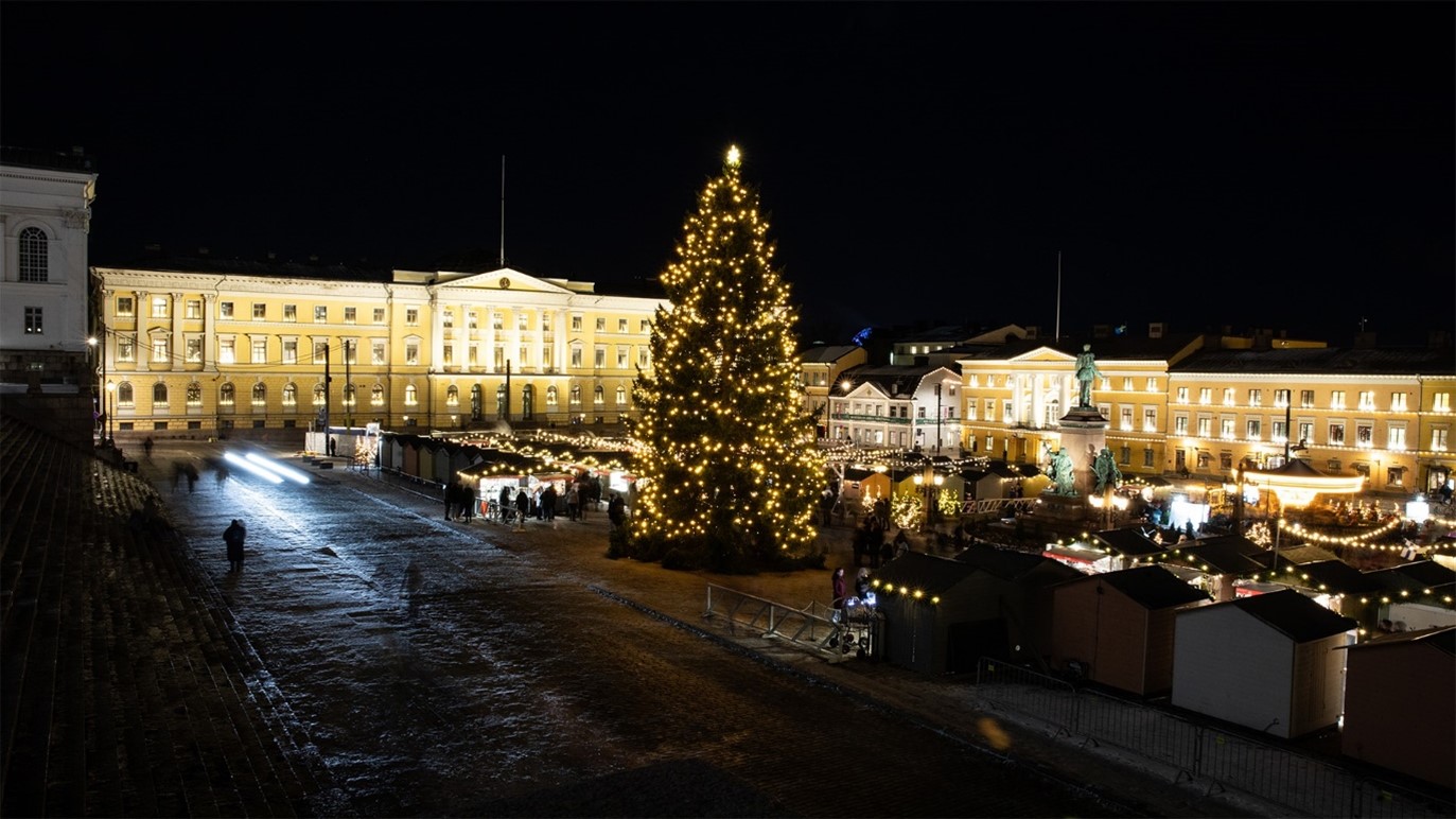 Illustrationen visar Senatstorget och en upplyst julgran i Helsingfors.