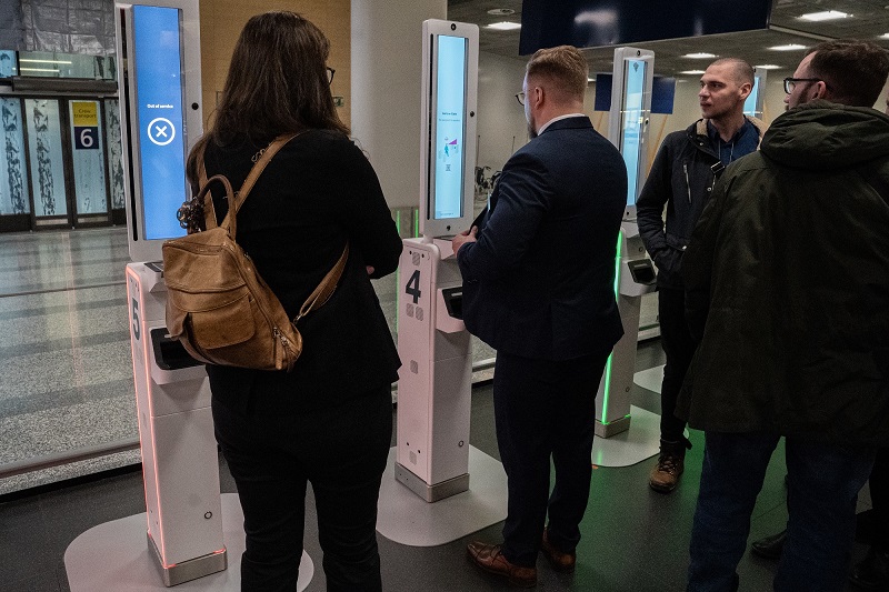 White border check automats in line. In front of one of them, there is a man trying the automat.